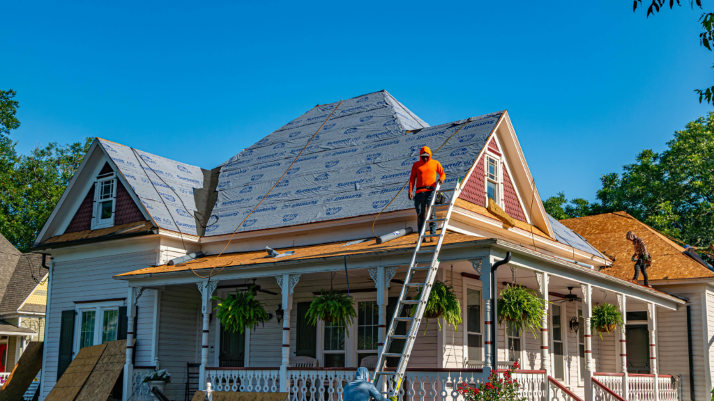 various workers on ladders repairing the roof of a house.